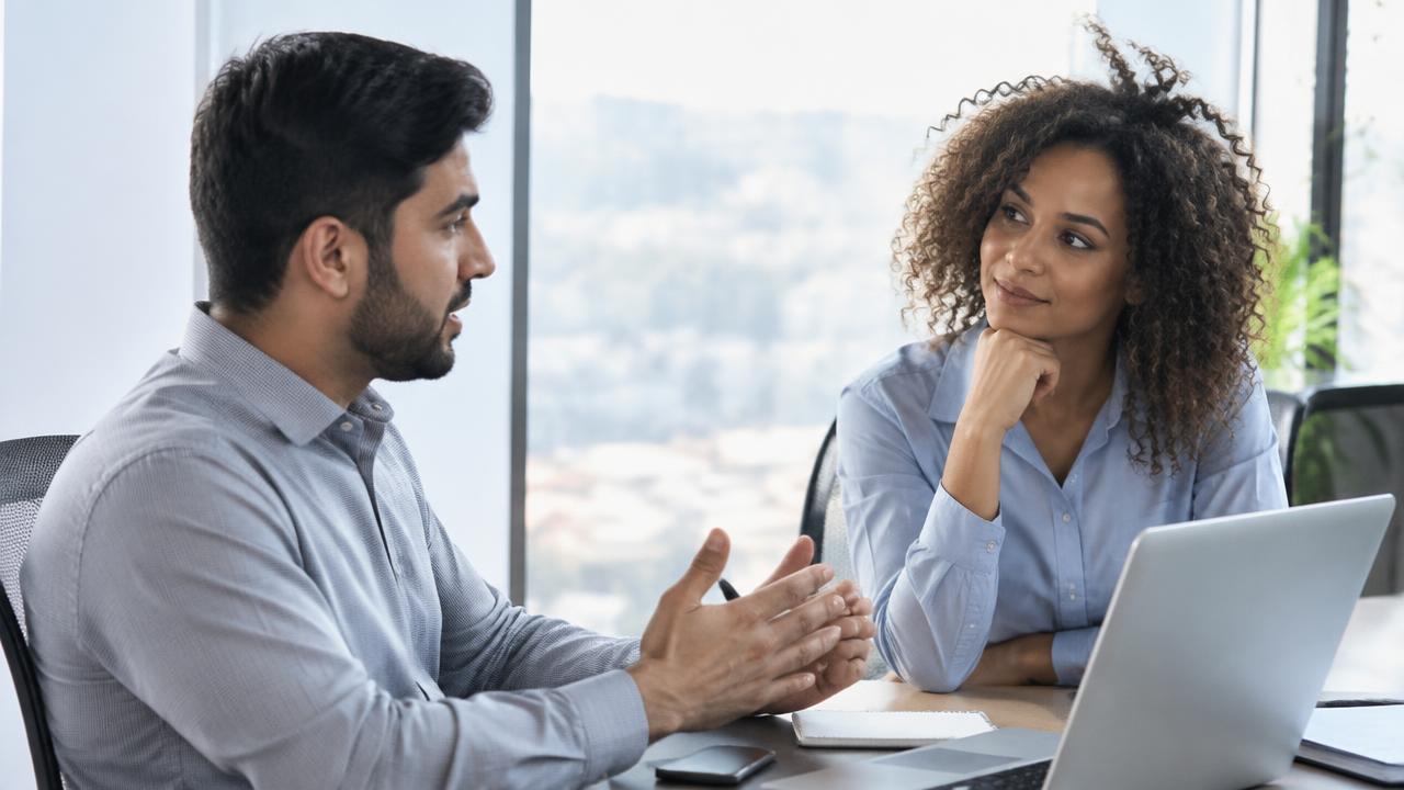 Two colleagues having a calm one-on-one feedback conversation at a desk